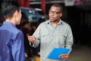 Mechanic explaining vehicle service details to a customer inside an auto repair shop