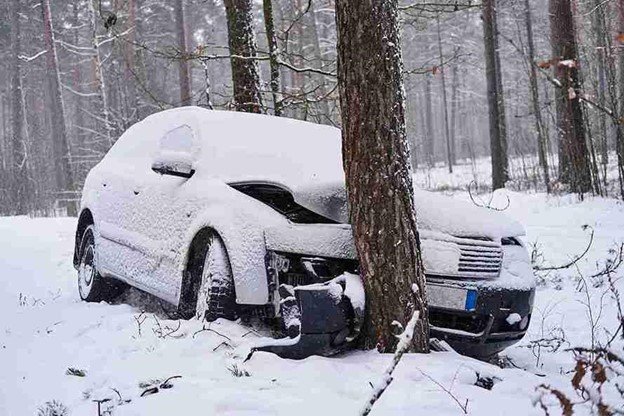 A Car got accident with a car tree on a snowy road