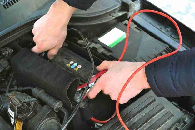 Driver waiting safely on the roadside with a warning triangle placed behind a broken-down car.