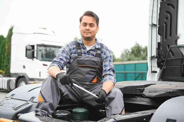 Professional towing technician wearing work gloves and safety gear inside a service garage