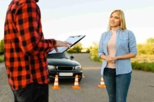Driver speaking with a roadside assistance worker next to a disabled car with safety cones