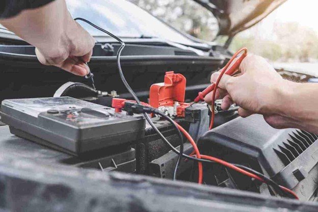 Portable jump starter with red clamp attached to a car battery terminal
