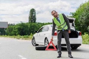 Roadside worker placing a reflective warning triangle behind stopped vehicles