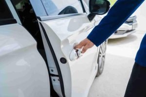 Close-up of a hand pulling a car door handle on a parked vehicle