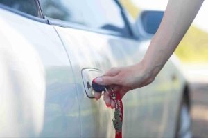 Close-up of a hand pulling a car door handle on a parked vehicle