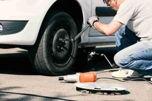 Technician using a jack to lift a vehicle during a tire change